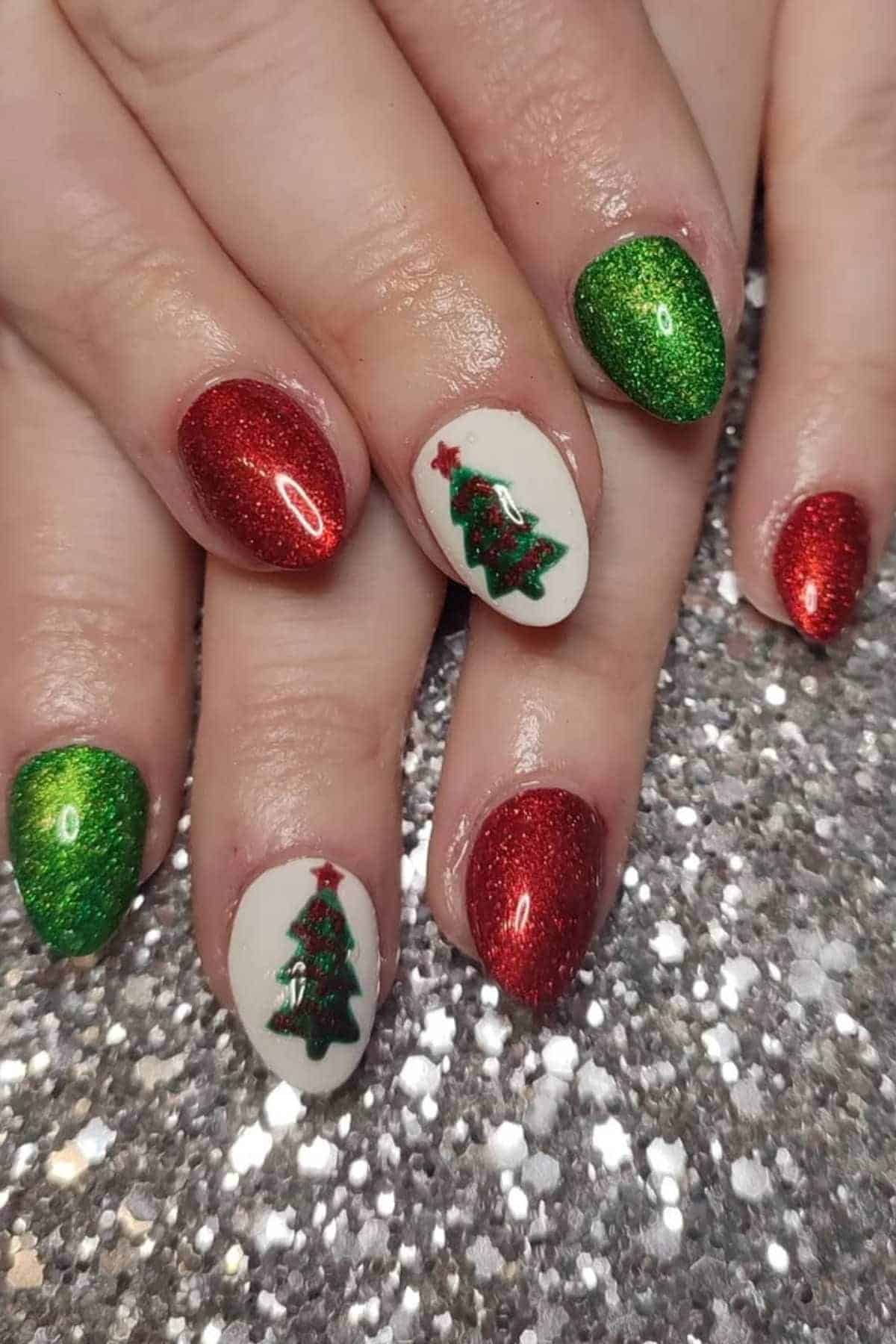 Fingernails painted with red and green glitter polish, and two nails featuring white polish with a Christmas tree design.