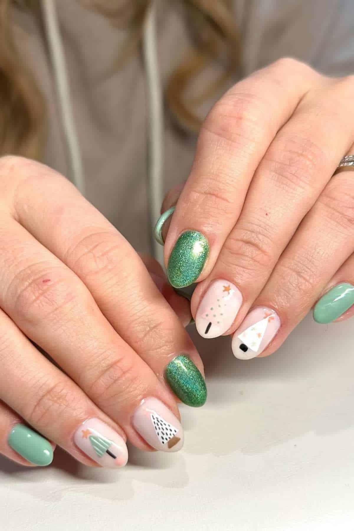 Hands with manicured nails painted in green and white shades, featuring Christmas tree and snowman designs on some nails.
