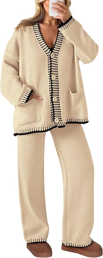 A person wears a beige loungewear set with black and white trim, large buttons, pockets, and brown slippers, taking a mirror selfie.