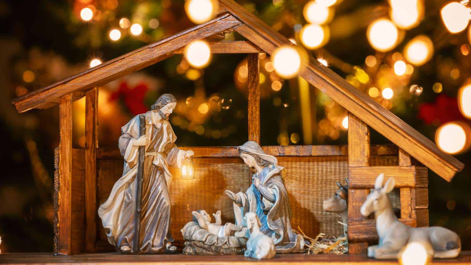 A nativity scene with figurines of Mary, Joseph, and baby Jesus in a wooden stable, surrounded by animals, with warm glowing lights in the background.