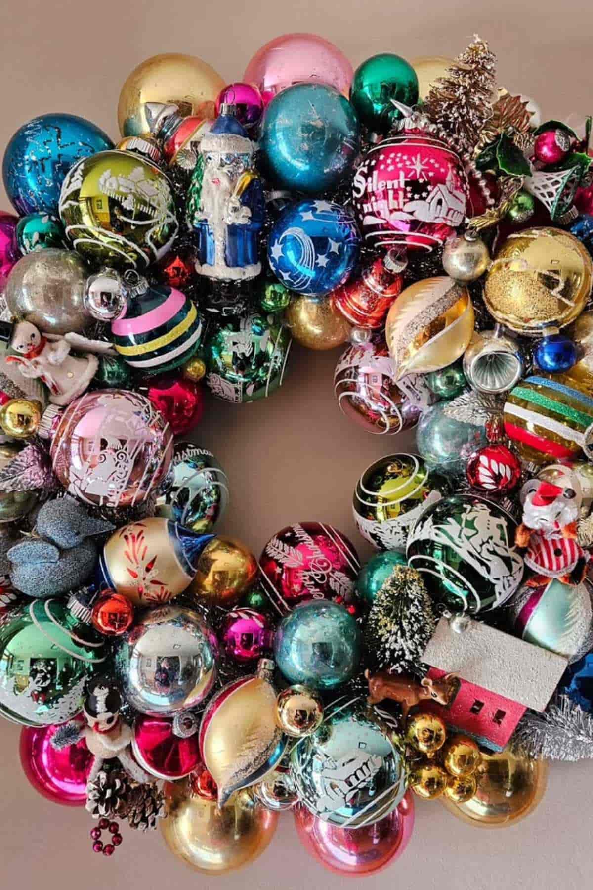 A holiday wreath made from colorful, vintage-style Christmas ornaments, including baubles, figurines, and small festive decorations.