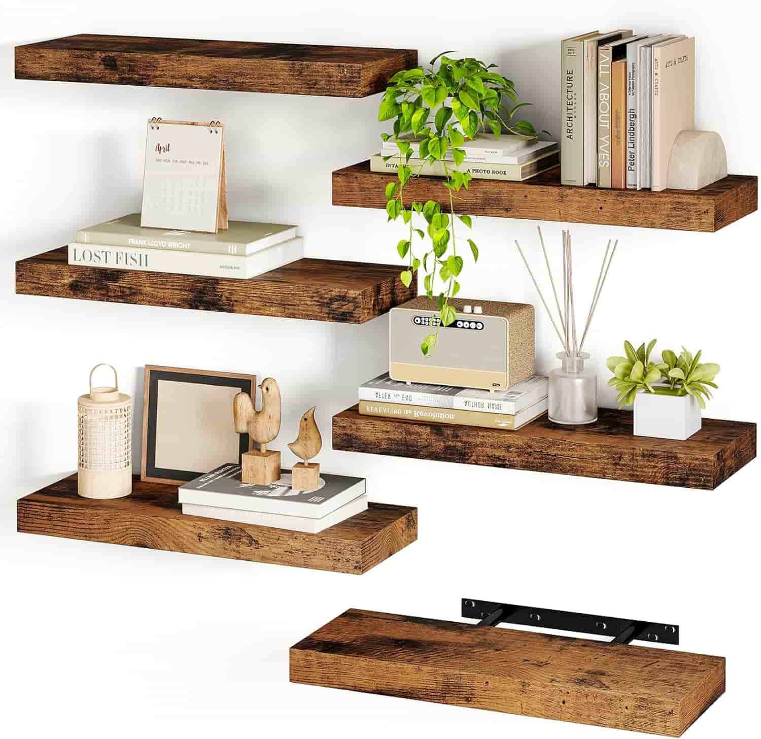 Six rustic wooden floating shelves are mounted on a wall, displaying books, plants, decorative objects, and a calendar; one shelf shows the mounting bracket.