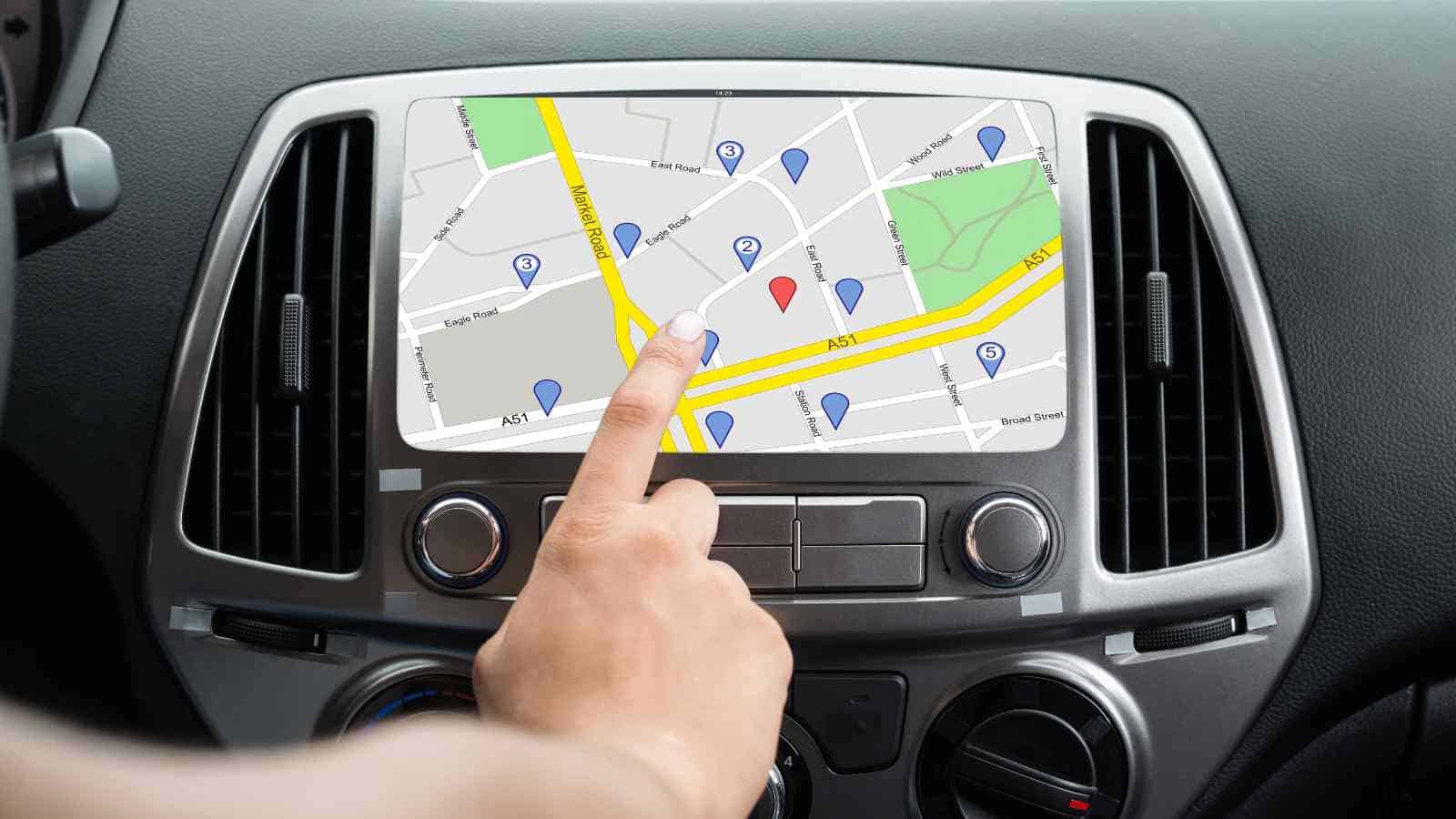 A hand points at a car navigation system screen displaying a city map with multiple location markers in various colors.