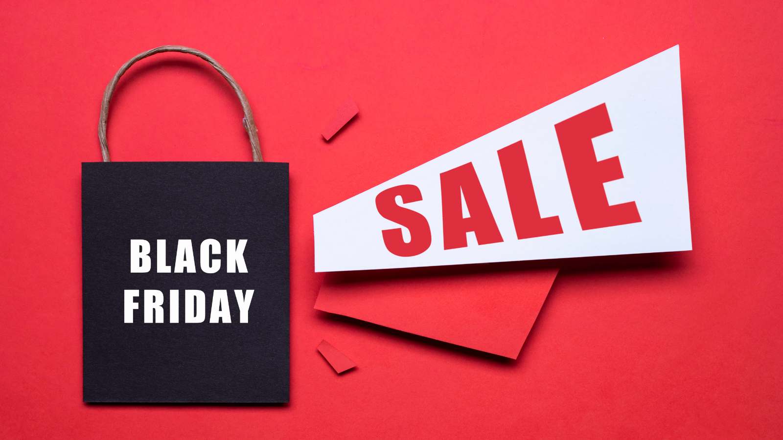A black shopping bag with "Black Friday" text next to a white and red sign displaying "SALE" on a red background.