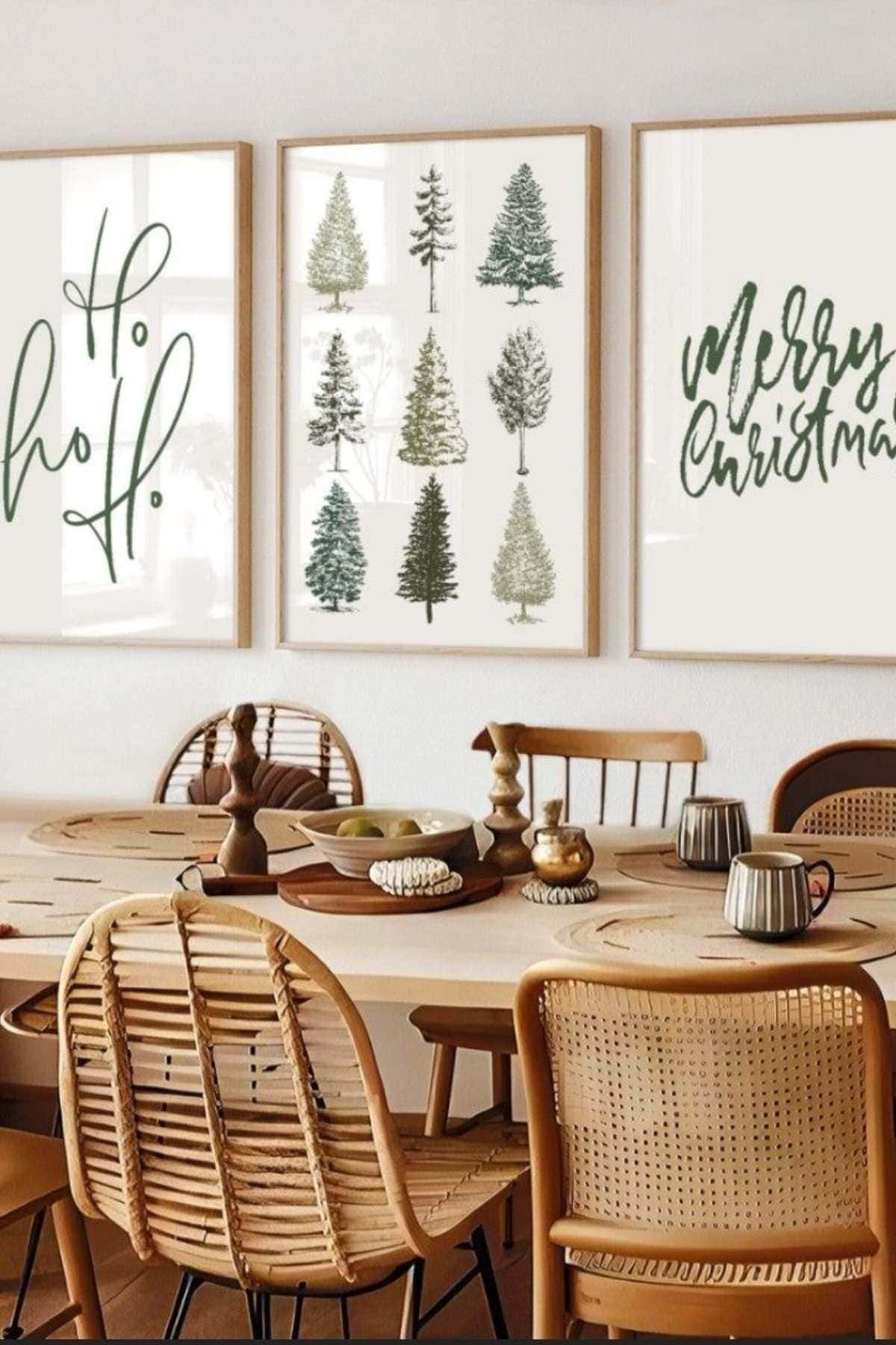 A dining area with a wooden table and chairs, decorated with festive wall art featuring "Ho ho ho," Christmas trees, and "Merry Christmas" in green lettering.