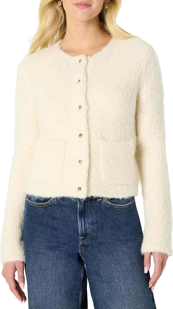 Woman wearing a cream-colored, textured button-up cardigan with patch pockets, paired with blue jeans.