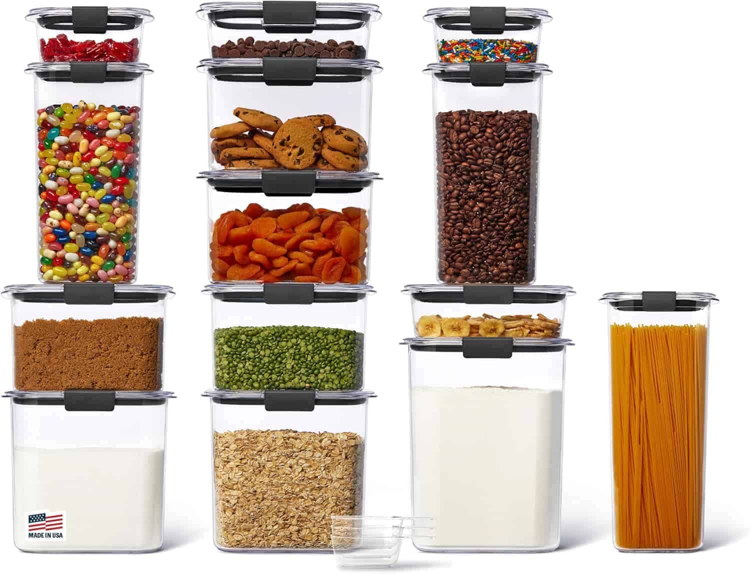 Thirteen clear plastic food storage containers filled with various dry foods, such as pasta, flour, oats, beans, candy, and cookies, are neatly stacked on a white surface.