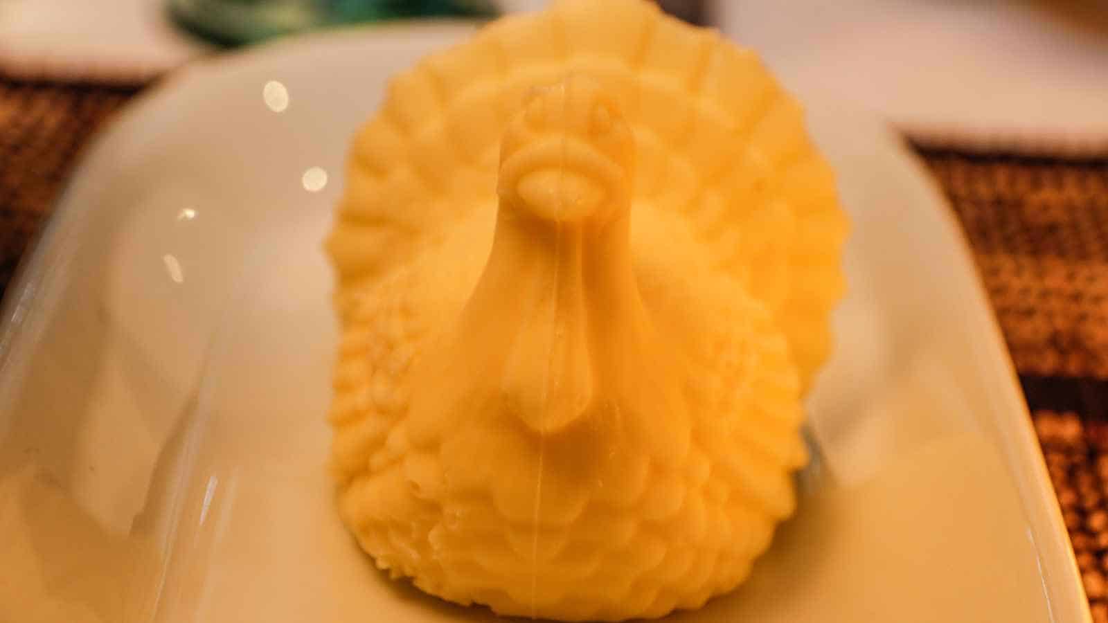 A molded butter sculpture shaped like a turkey is placed on a white plate.