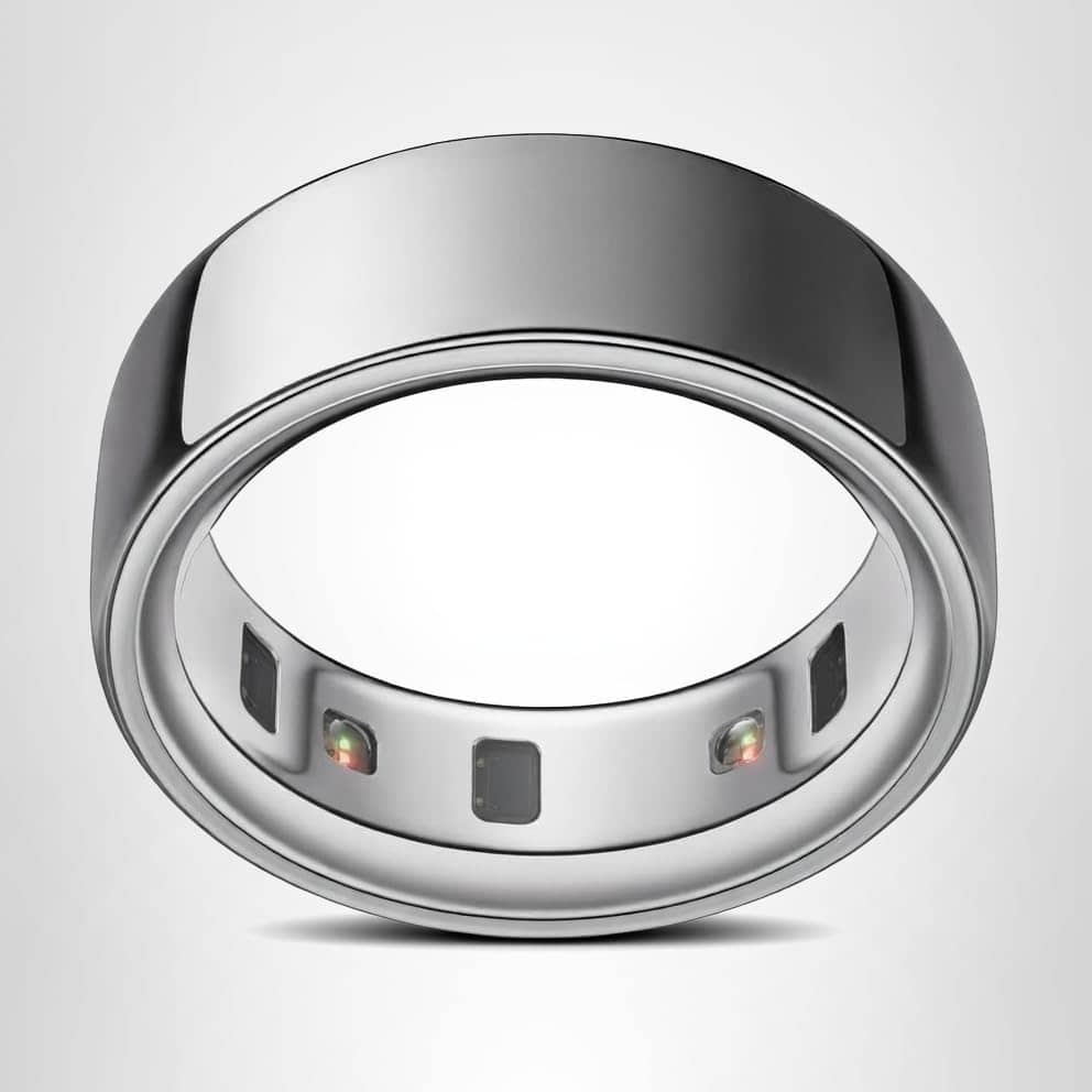 A silver smart ring with a smooth, shiny exterior and small sensors embedded on the inner band, displayed against a plain white background.