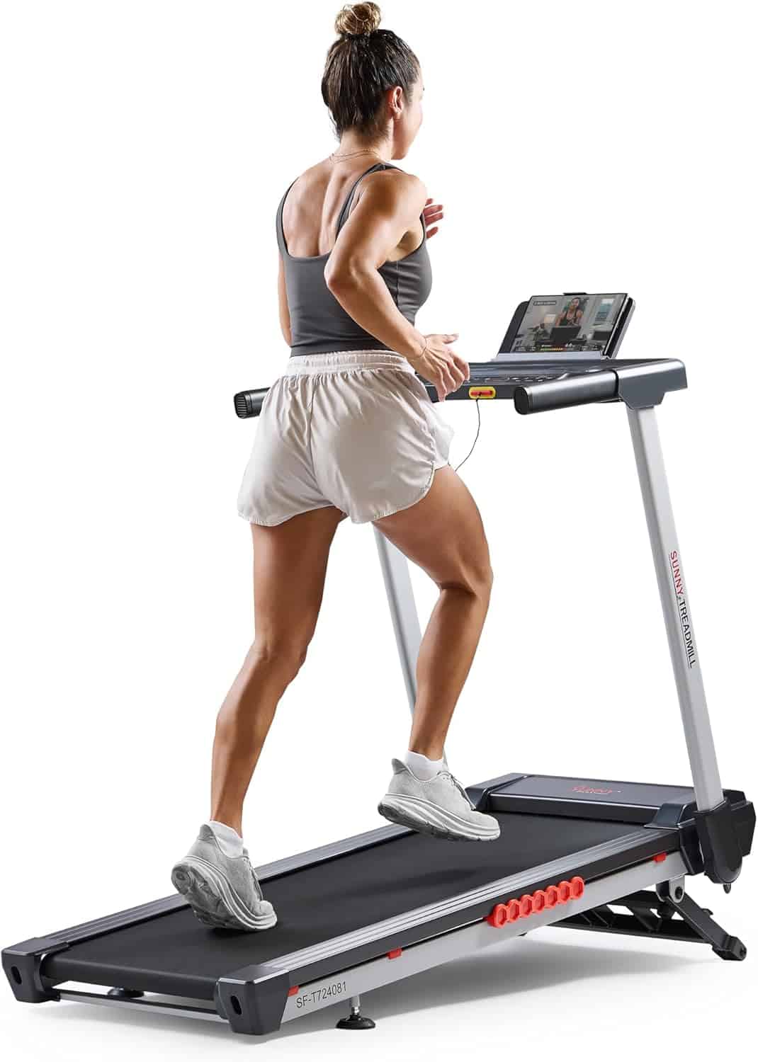 A woman runs on a treadmill while watching a screen, wearing athletic clothing and sneakers.