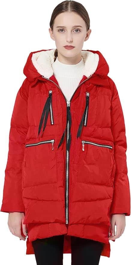 A woman wearing a red hooded puffer coat with black zipper and ribbon details, over a white turtleneck sweater, standing against a plain background.