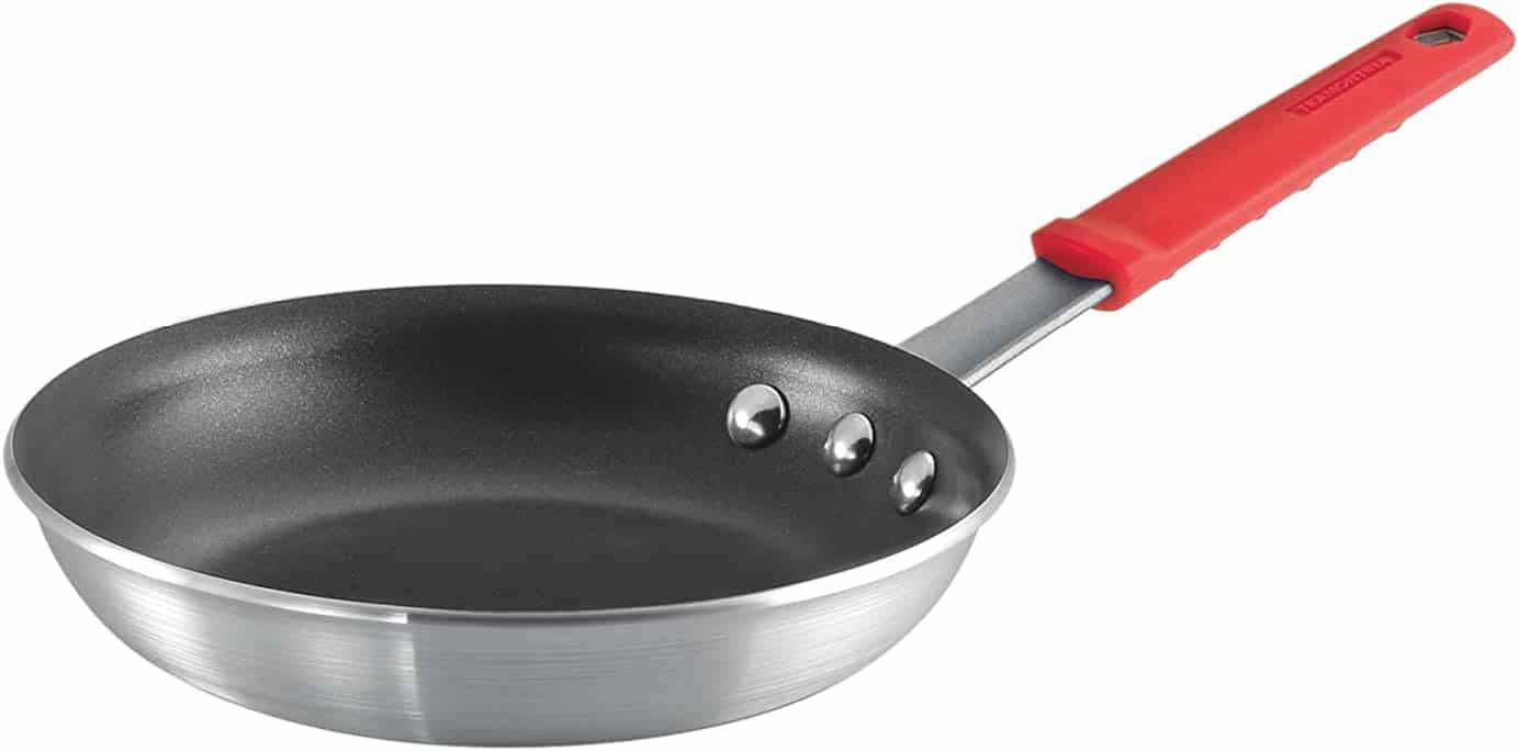 A small nonstick frying pan with a metal body and a red, heat-resistant handle is shown against a white background.