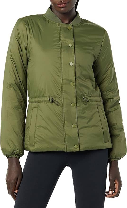 A person wearing an olive green quilted button-front jacket with a drawstring waist and black pants, shown from mid-thigh up.