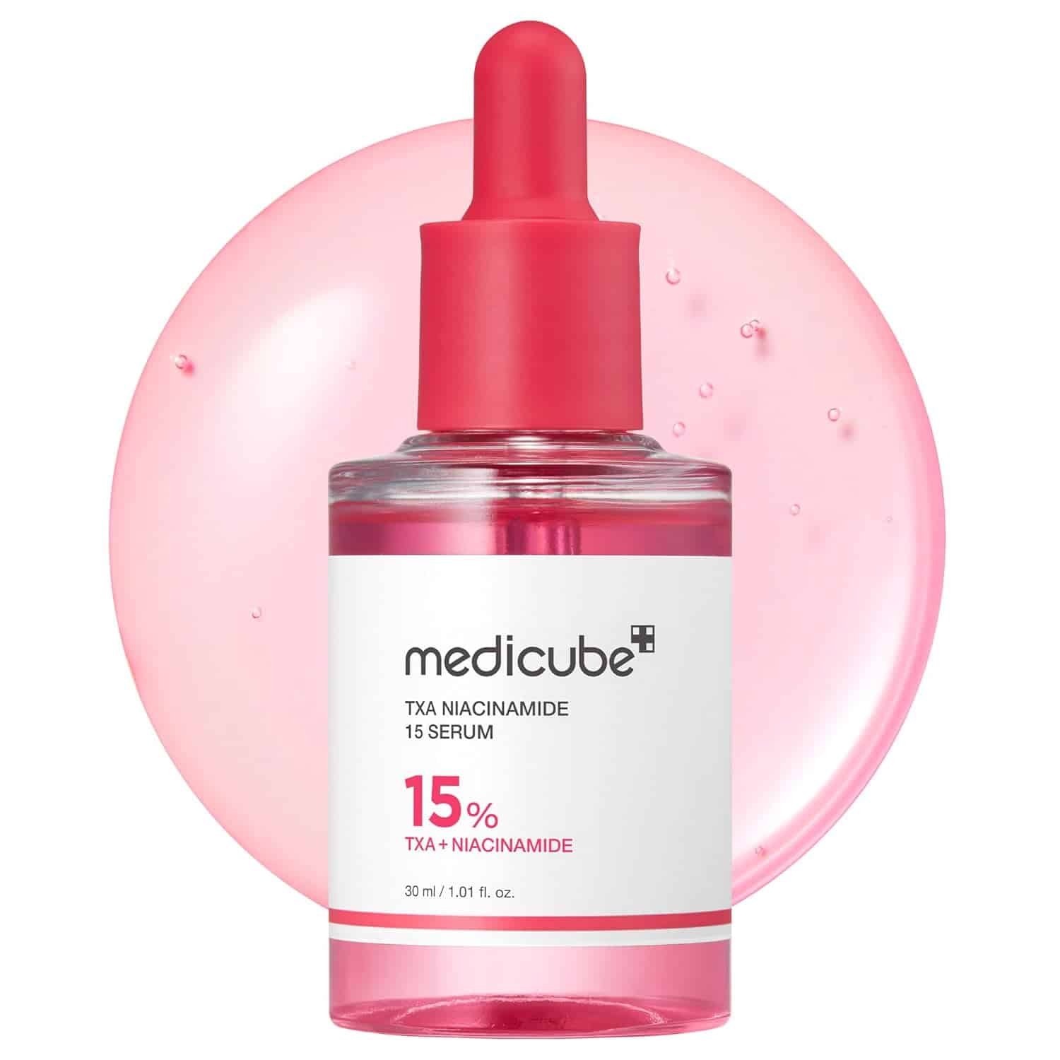 A clear bottle of Medicube TXA Niacinamide 15 Serum with a red dropper cap, labeled 15% TXA + Niacinamide, placed in front of a pink liquid background.