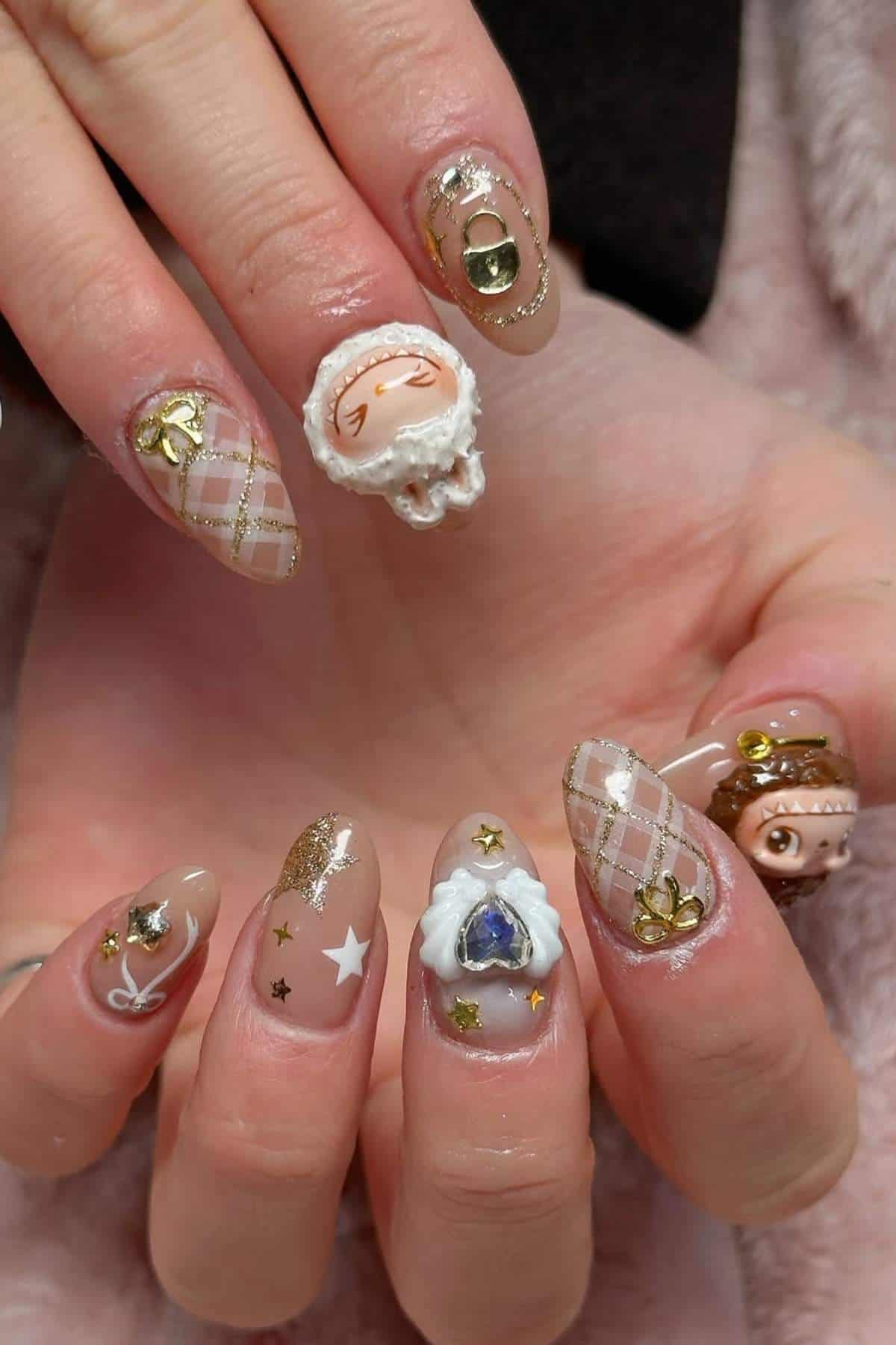 A hand with long, almond-shaped nails featuring intricate nail art, including gold accents, plaid patterns, stars, bows, and raised 3D decorations shaped like faces and objects.