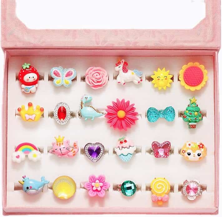 A pink box displays 24 colorful children's rings with designs including animals, flowers, hearts, a butterfly, a unicorn, and other playful shapes.