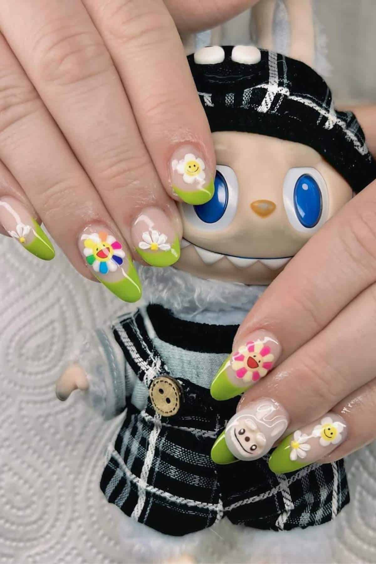 Hands with green-tipped nails featuring colorful flower and smiley face designs, held over a doll dressed in a plaid outfit with blue eyes.