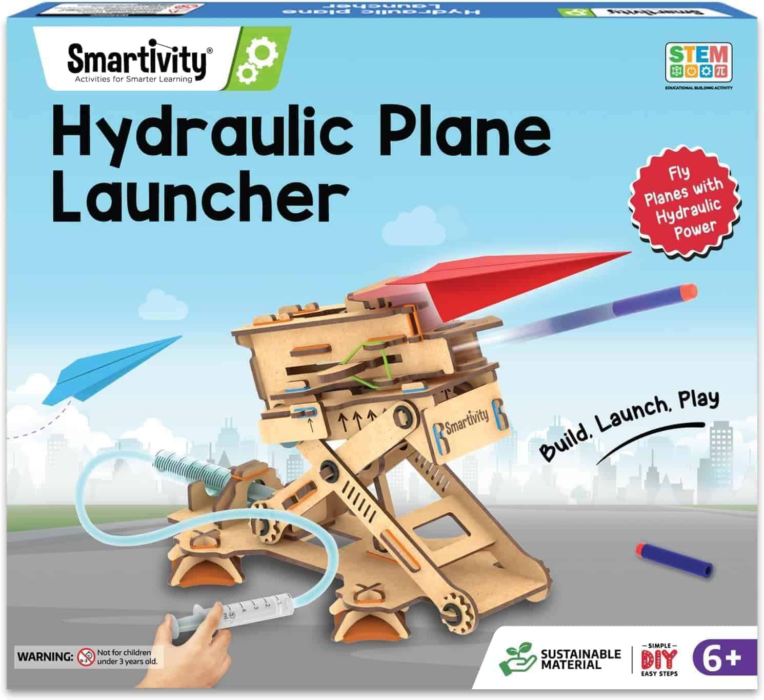 Box for "Smartivity Hydraulic Plane Launcher" STEM toy kit, featuring an assembled wooden launcher, paper planes, and branding. Suitable for ages 6 and up.