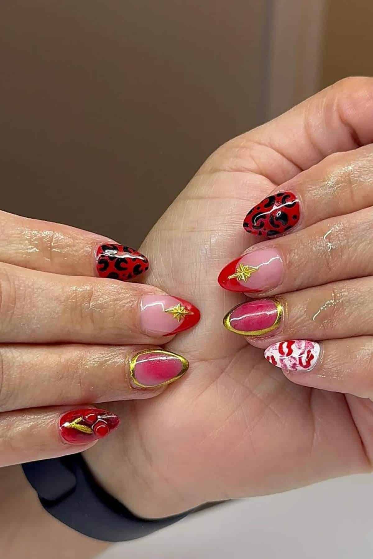 Hands with almond-shaped nails featuring red, black, gold, and white nail art designs, including stars, hearts, swirls, and French tips.