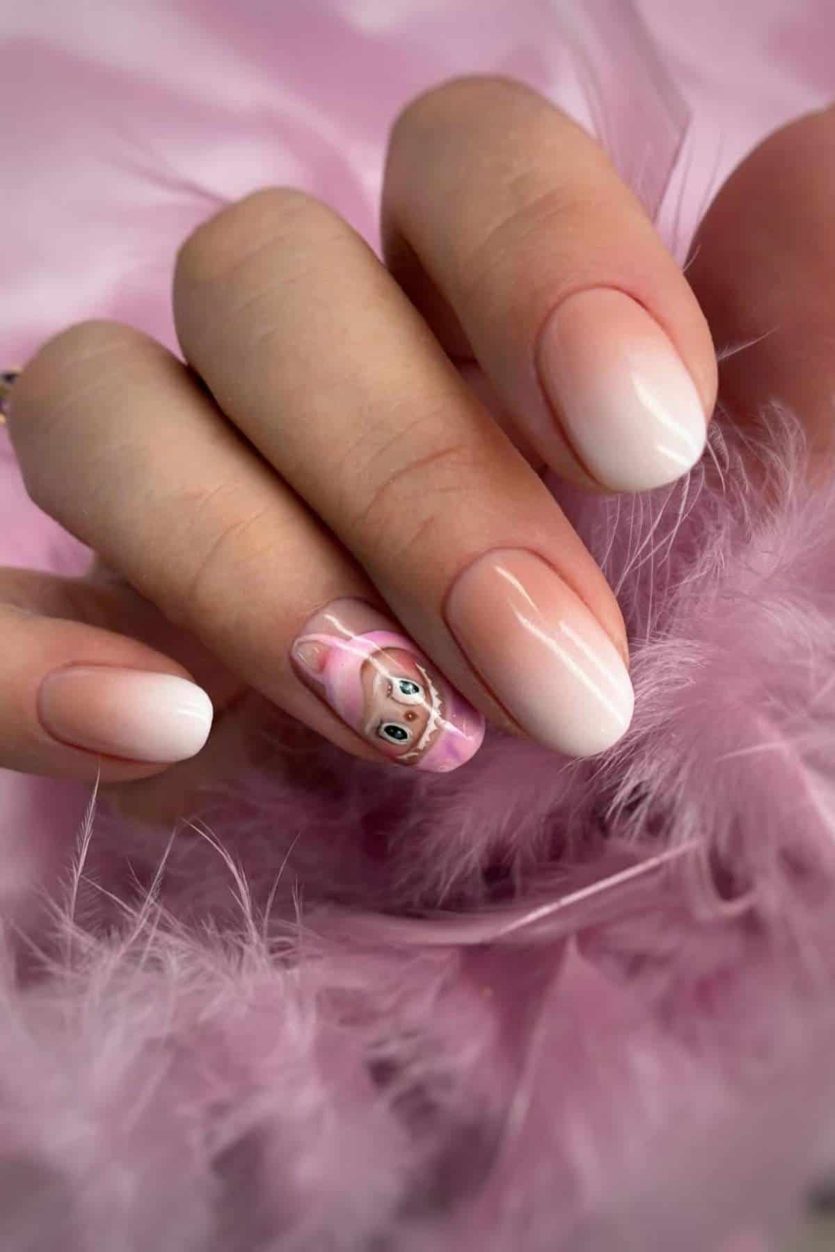 A hand with light pink ombre nails, one nail featuring detailed nail art of a cartoon animal face, holding pink feathers.
