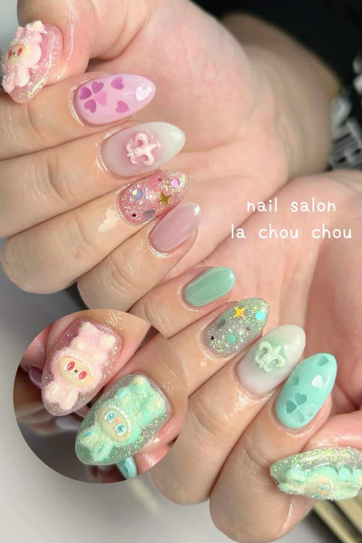 Close-up of hands showing pastel-colored nail art with 3D characters, glitter, hearts, stars, and other decorative designs on each fingernail.