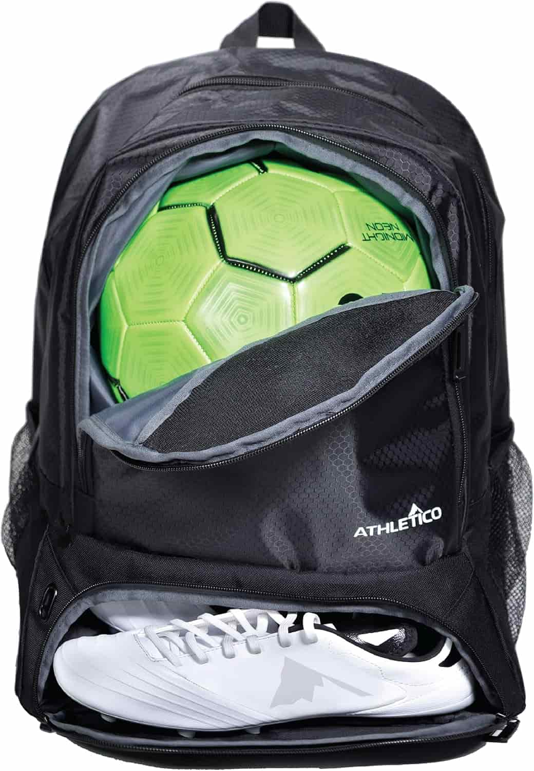 A black backpack with a green soccer ball in the main compartment and white cleats in a lower zippered shoe pocket.