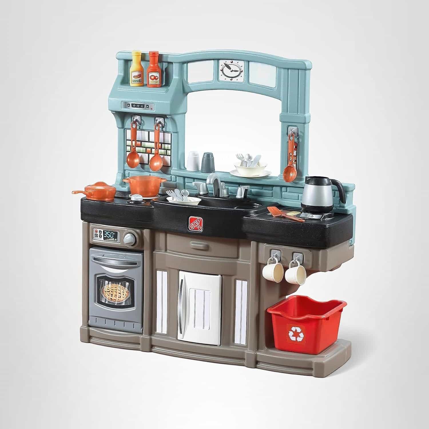 Toy kitchen set with stove, oven, sink, cookware, utensils, dishes, and a red recycle bin, all arranged against a plain white background.