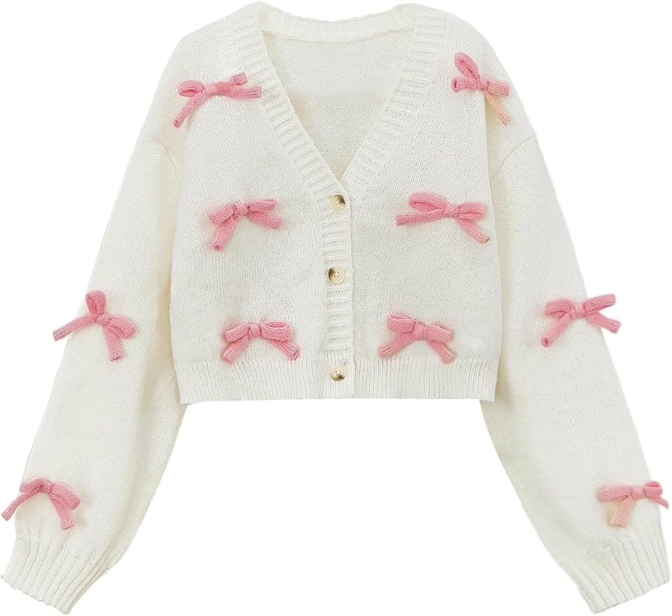 A white knit cardigan with gold buttons, decorated with multiple pink bows on the front and sleeves.