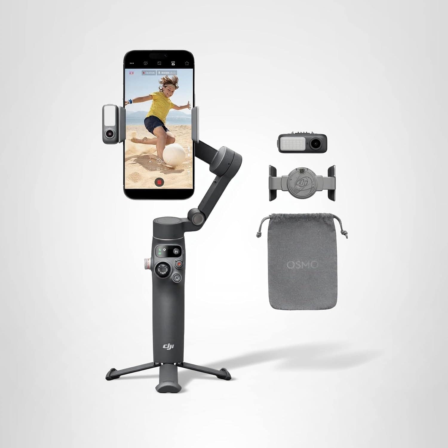 DJI smartphone gimbal with attached phone, tripod base, magnetic clamp, carrying pouch, and additional accessories on a plain background.