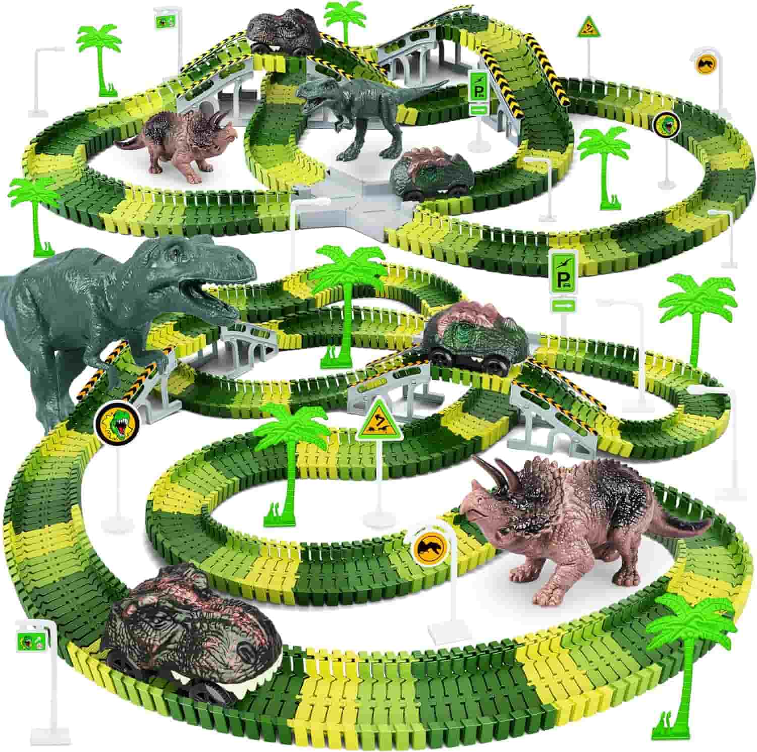 A green and yellow toy racetrack is set up with plastic dinosaurs, palm trees, road signs, and streetlights arranged around the track.