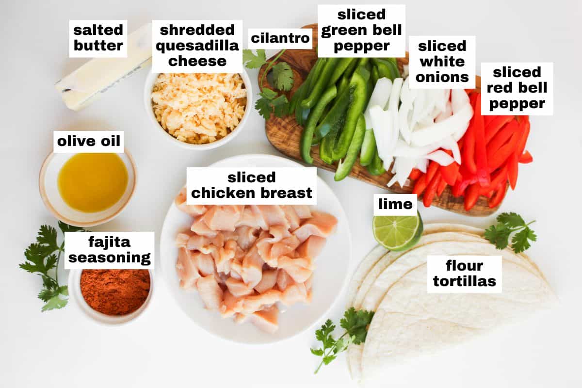 Chicken fajita ingredients arranged on a white surface, including sliced chicken breast, bell peppers, onions, cheese, seasonings, butter, oil, lime, tortillas, and cilantro.