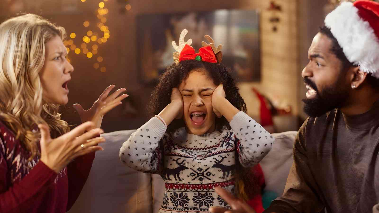 A woman and man argue loudly while a young girl between them covers her ears and closes her eyes, looking distressed. Holiday decorations are in the background.