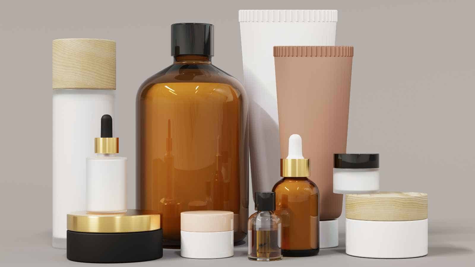 A variety of cosmetic containers, including bottles, jars, and tubes in neutral shades, are displayed on a beige surface.