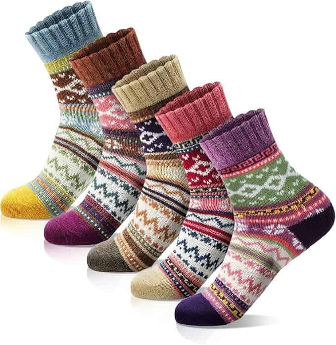 Five pairs of colorful wool socks with various winter patterns and ribbed cuffs, displayed in a row on a white background.