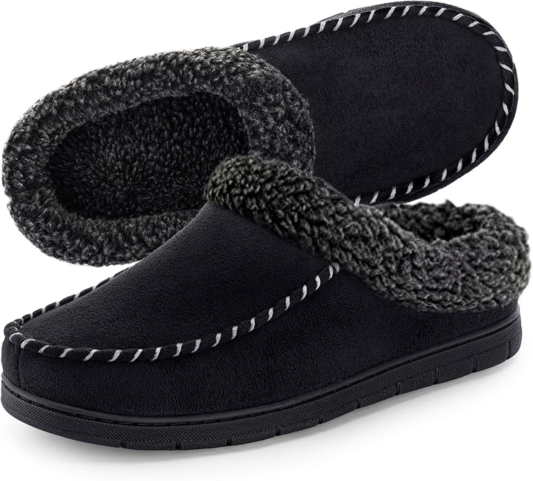 A pair of black slip-on slippers with thick, textured gray lining and stitched detailing on the edges, shown on a white background.