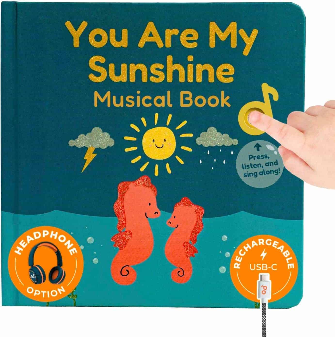A child's hand presses a musical button on the cover of the "You Are My Sunshine Musical Book," featuring seahorses, a sun, and icons for headphone and USB-C rechargeable options.