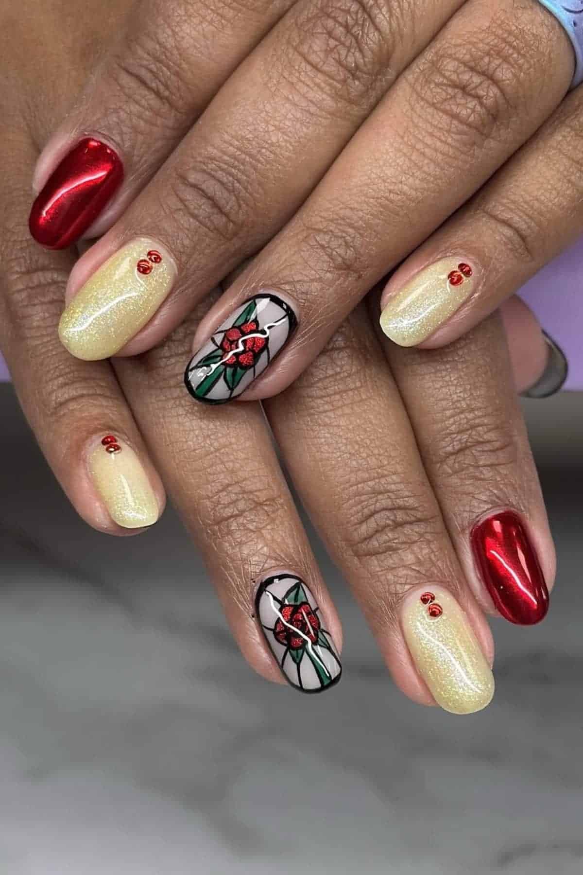 Hands with manicured nails; some painted red, some pale yellow with small red gems, and two accent nails with a holly and berry design.