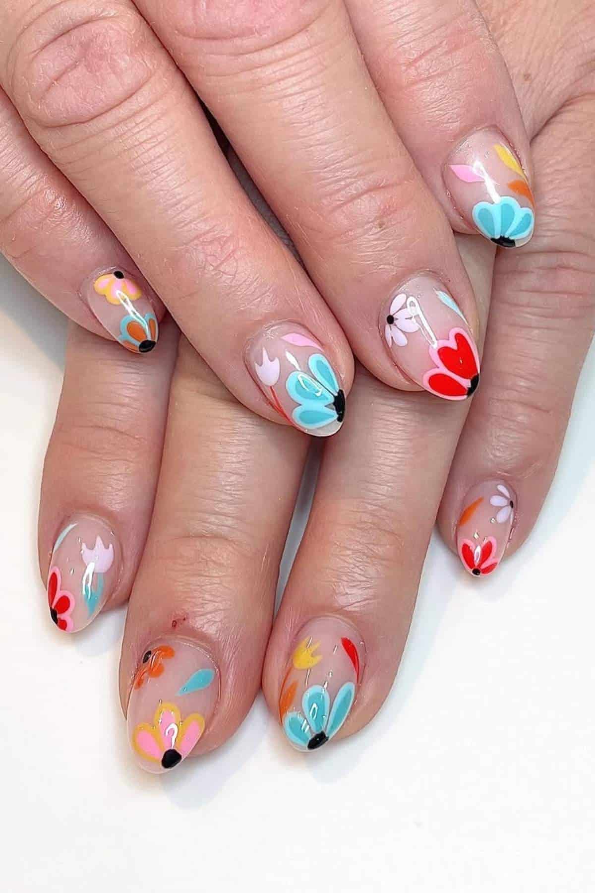 Close-up of hands with nails painted in colorful floral designs on a light, natural base.
