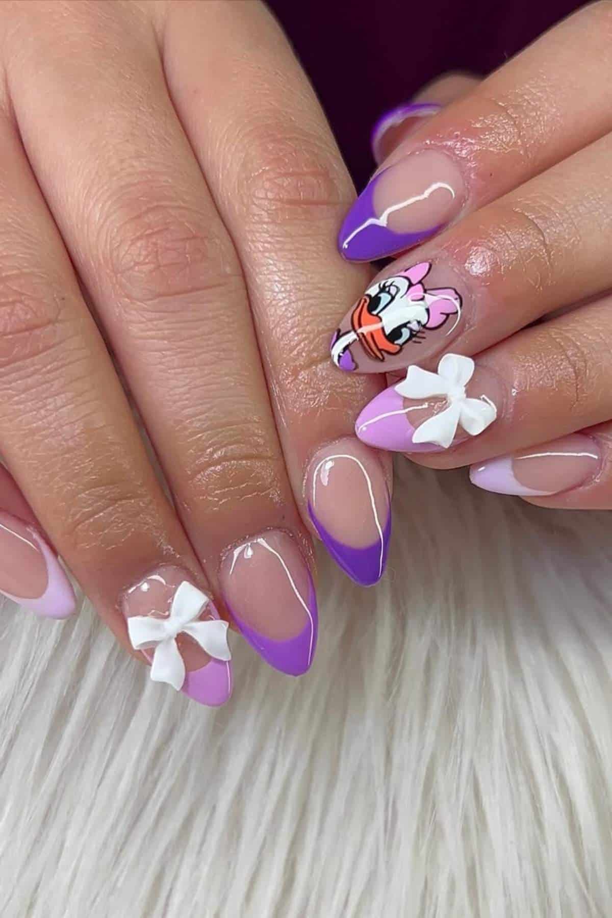 Hands with almond-shaped nails featuring purple French tips, 3D white bows, and a cartoon character design on one nail, displayed on a white textured surface.