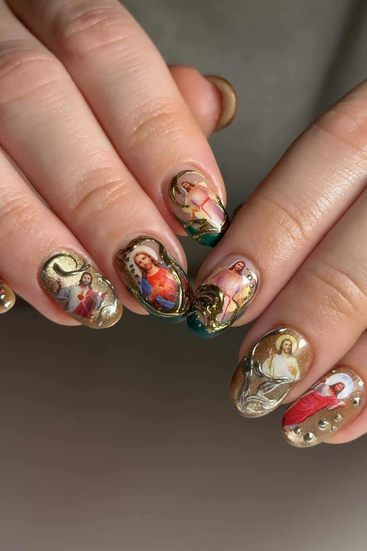 Close-up of hands with fingernails painted in gold and decorated with detailed religious iconography, including images of saints and Jesus.