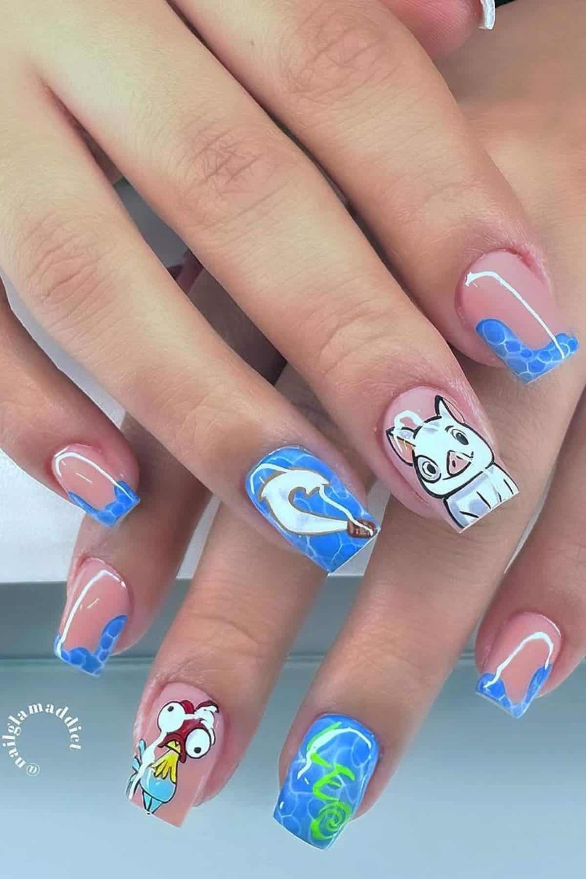 Hands with square-shaped nails featuring blue french tips and cartoon designs, including a rooster, pig, turtle, and wave on a nude base.