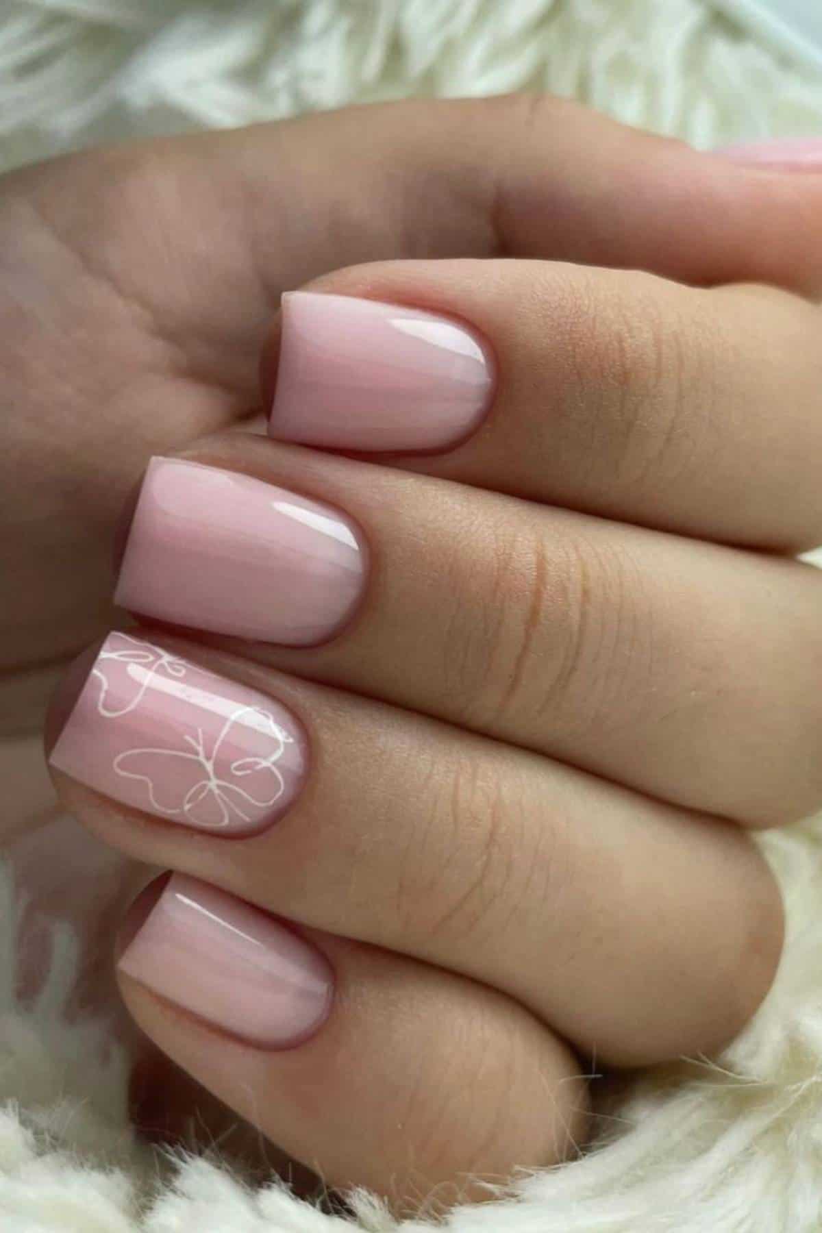A hand with short, glossy, pale pink manicured nails; the ring fingernail features a delicate white line art design.