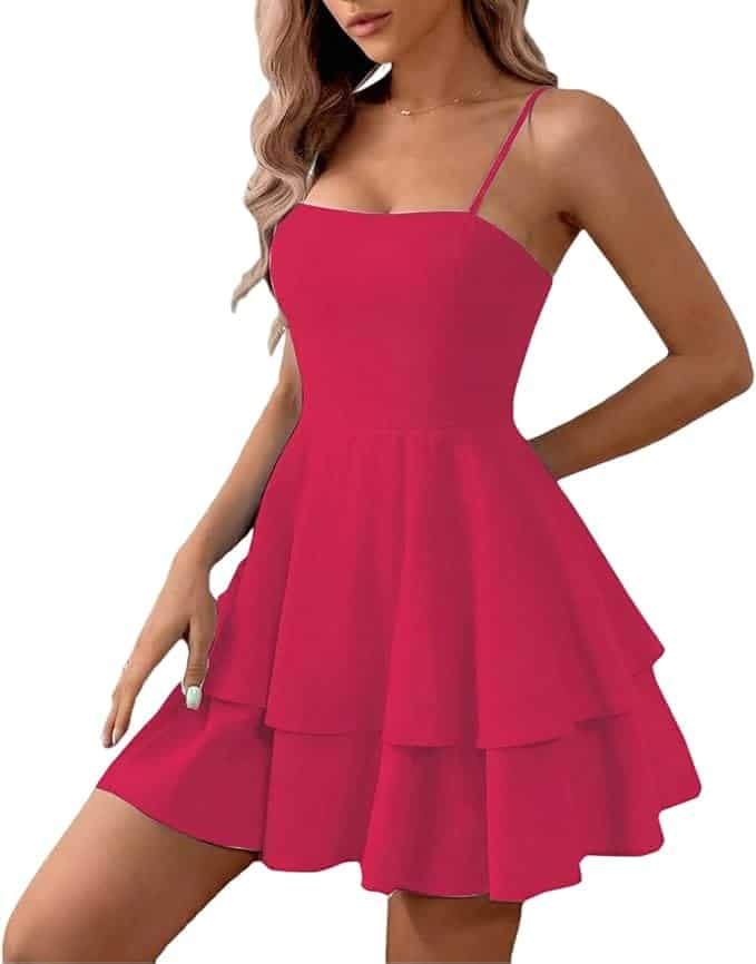 Woman wearing a sleeveless, bright pink tiered mini dress with spaghetti straps and a fitted bodice against a white background.