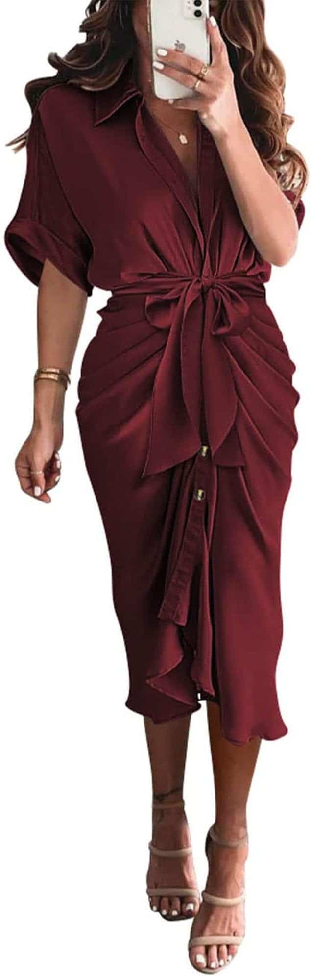 Woman wearing a burgundy midi dress with a front bow, short sleeves, button details, and nude heeled sandals, taking a mirror selfie.