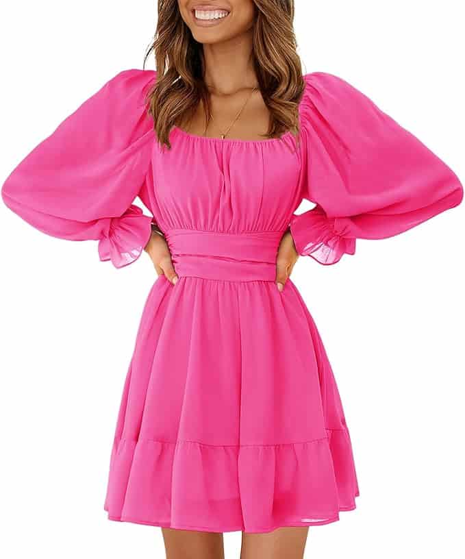 Woman wearing a bright pink, long-sleeve, puff-shoulder dress with a fitted waist and ruffled hem, standing with hands on hips and smiling.