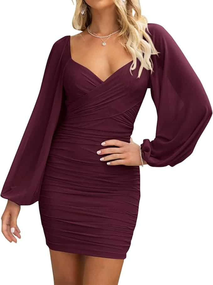 Woman wearing a fitted, long-sleeve, deep burgundy mini dress with a V-neckline and ruched detailing, accessorized with layered necklaces.