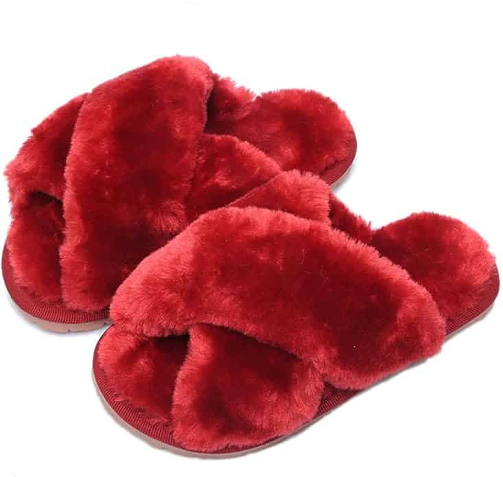 A pair of red, fluffy slippers with crisscross straps and open toes, placed side by side on a white background.