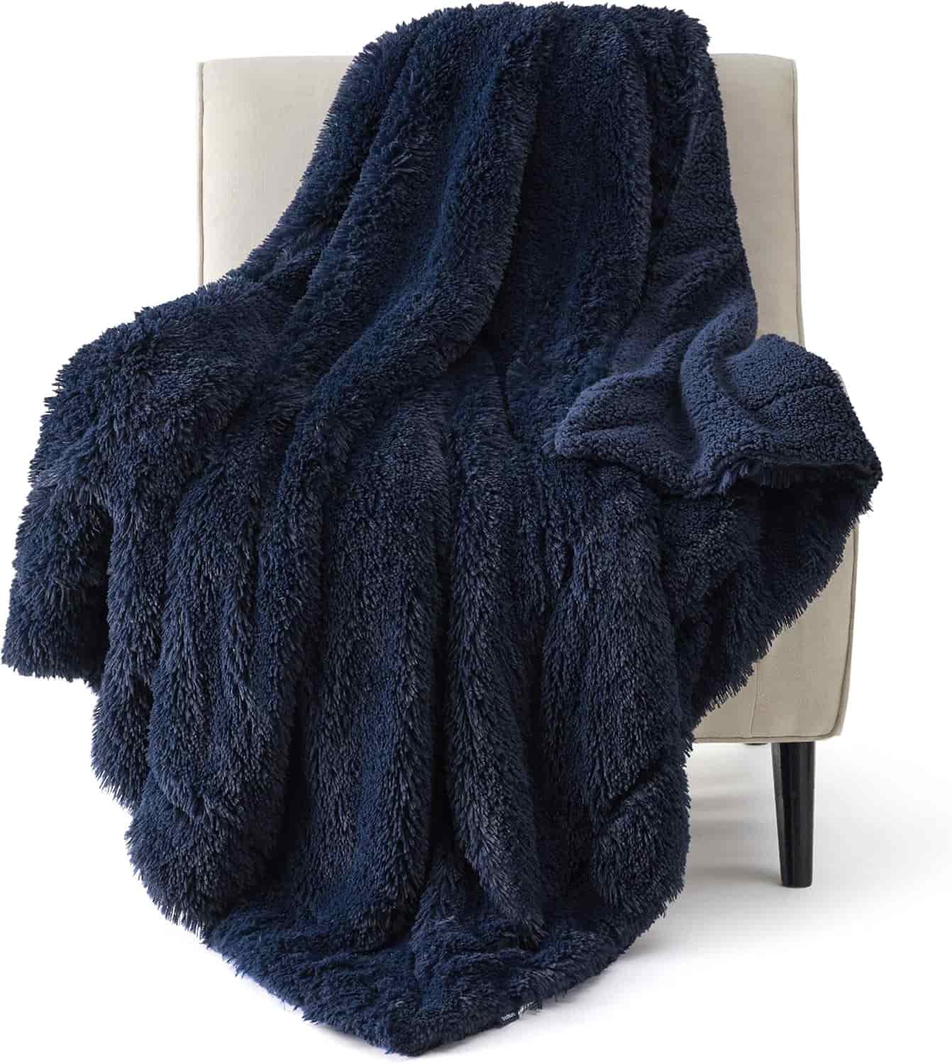 A plush, dark blue faux fur blanket draped over a light beige chair with black legs.