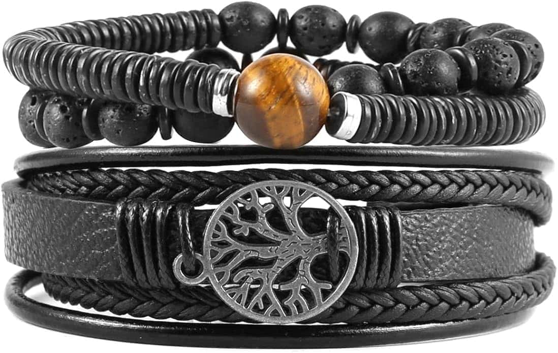 A stack of four black bracelets, including beaded, braided, and leather designs, with one featuring a silver tree of life charm and another with a single brown bead.