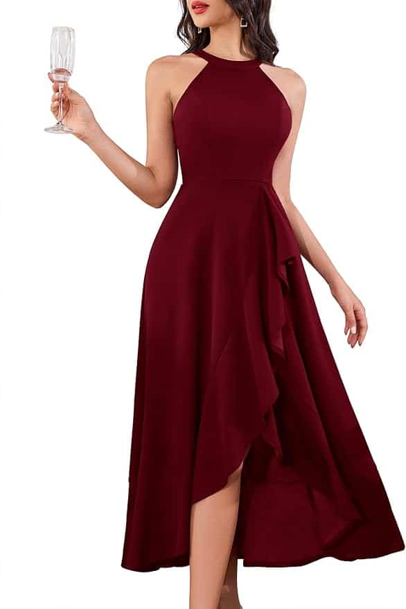 Woman wearing a sleeveless, burgundy high-low dress holding a champagne glass, shown from neck to mid-calf against a plain white background.